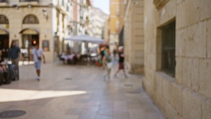 Blurred outdoor scene showing people walking and sitting at a cafe in a european street with buildings and storefronts in the background