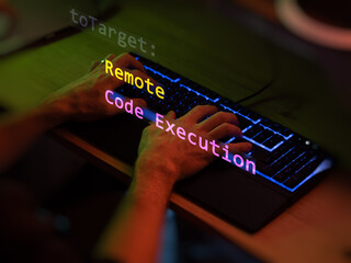 Cyber attack remote code execution text in foreground screen, hands of a anonymous hacker on a led...