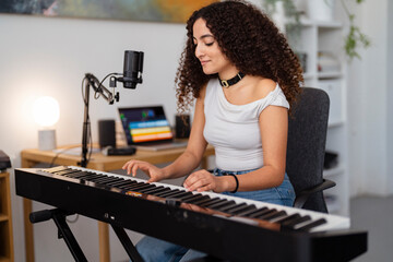 young woman is focused on her keyboard practice in a home studio, sitting by a microphone in a creative and professional setup that highlights her musical dedication and skill.