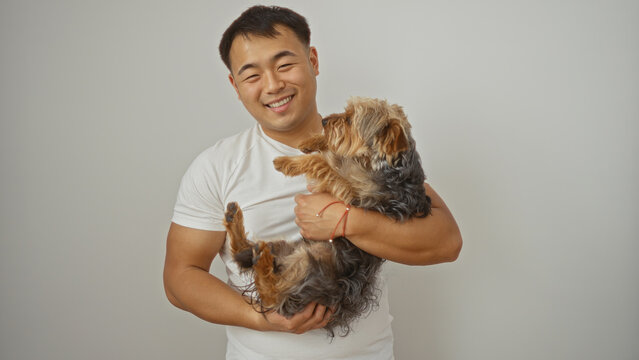 Smiling young man holding his pet dog against a white isolated background.