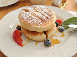 Top down view of a delicious pancake served with maple syrup on plate. Focus on pancake, blurred background