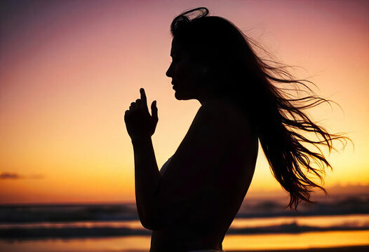 Silhouette of a woman against the sunset sky by the sea