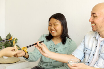 Asian Father and Daughter Eating Korean Style Barbeque Meat With Family