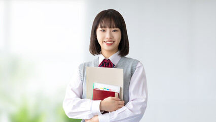 Fototapeta premium 教科書を持つ笑顔の受験生・制服姿の女子高校生