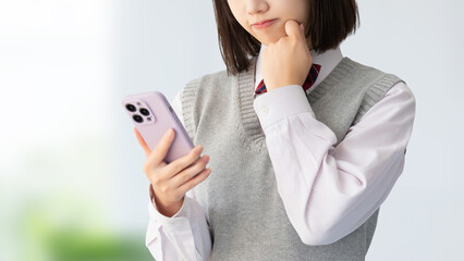 スマートフォンを見て考える受験生・制服姿の女子高校生