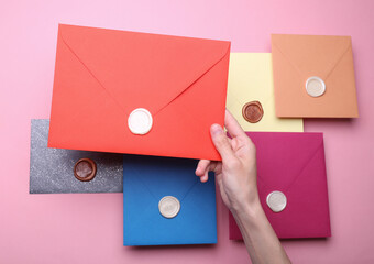 Girl sealing envelope with wax sealing stamp on pink background
