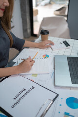 A woman is sitting at a desk with a notebook and a laptop