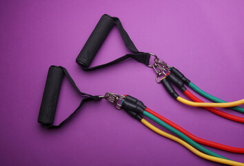 Rubber expander with handles for fitness on purple background