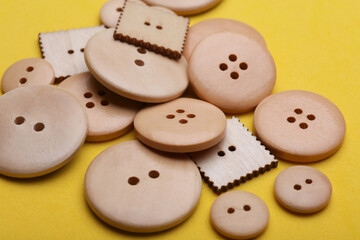 Wooden buttons on a yellow background close up