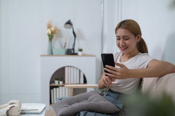 A woman is sitting on a couch and looking at her cell phone