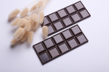 Dark chocolate bars with lagurus flowers on a white background