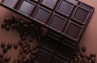 Dark chocolate bars with coffee beans on brown background