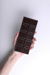 HAnd holding Dark chocolate bar on white background