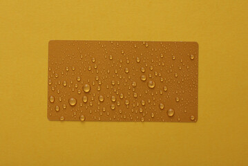 Golden business card with water drops on yellow background