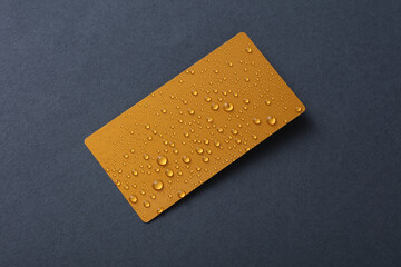 Golden business card with water drops on dark gray background