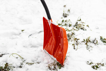 Clearing snow with orange snow shovel. Snow removal in winter