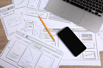 Developing UI design. Sketches of website wireframes, laptop, smartphone and pencil on wooden...