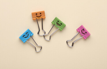 Binder clips with a smiling faces on beige background