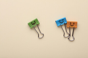 Binder clips with a smiling faces on beige background