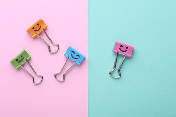 Binder clips with a smiling face on pink blue background