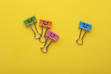 Binder clips with a smiling face on yellow background. Business concept. Creative layout