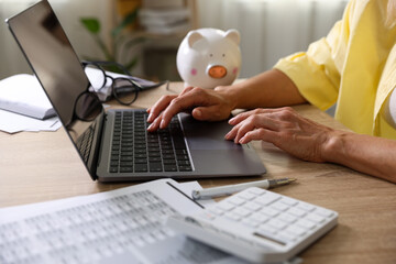 Budget planning. Woman using laptop at table indoors, closeup