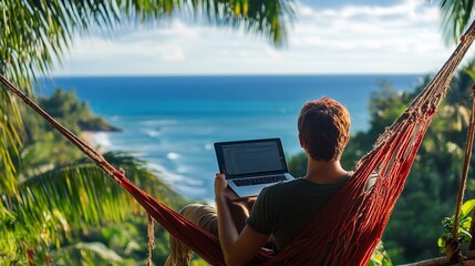 A man relaxes in a hammock with a laptop while overlooking a beautiful tropical beach.