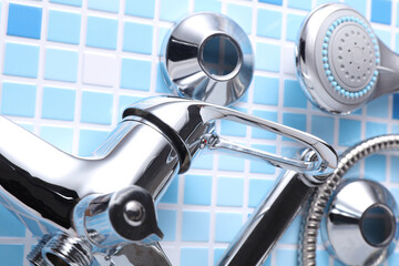 Parts of disassembled bathtub faucet with shower on tile background