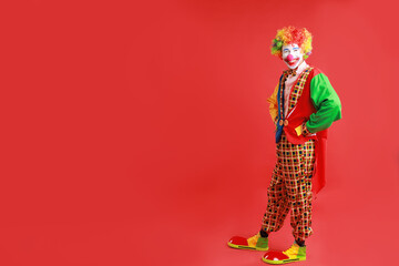 Portrait of happy clown on red background, space for text