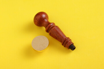 Vintage personal stamp with wooden handle and bronze head on yellow background.