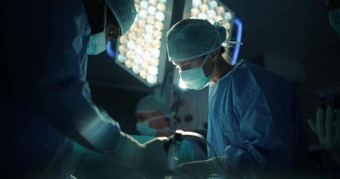 Portrait of a Female Surgeon Wearing Sterile Gear in Operating Room, Collaborating with a Professional Hospital Team, Executing a Surgery to Save Their Patient's Life and Remove a Cancer Tumor