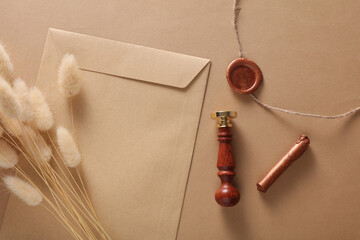 Envelope with wax seals and vintage stamp, thread, lagurus flowers on beige background. DIY, Gift...