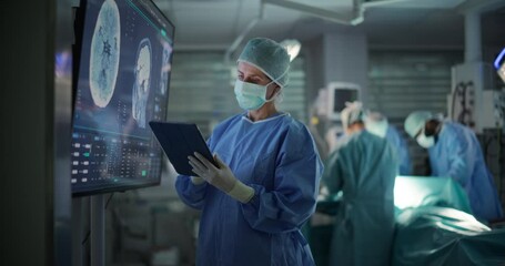 Lead Surgeon Reviews Critical Brain Scans Displayed on a Monitor as Well as Health Data on a Tablet Computer. Her Team Preparing as She Plans the Surgical Approach for the Operation - Powered by Adobe