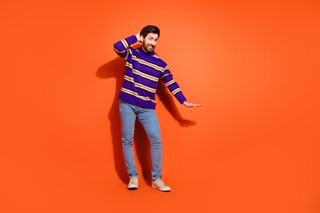 Full size photo of nice young male show measure wear trendy striped violet outfit isolated on orange color background