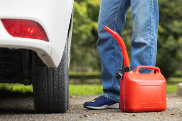 young man holds red gallon of gasoline which is reserve gasoline for emergency use when running out...