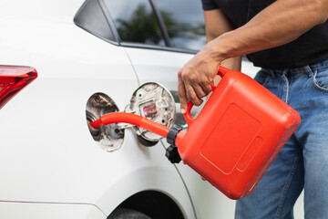 young man holds red gallon of gasoline which is reserve gasoline for emergency use when running out...