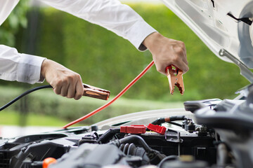 mechanic from the service center is helping to jump start the car battery for customer who has a...