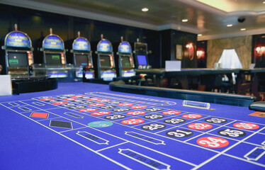 Teil von Spieltisch in Kasino auf Kreuzfahrtschiff mit Slotmaschinen im Hintergrund Glücksspiel -...