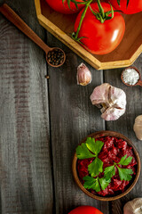 Homemade tomato sause near ingredients - garlic, spices - on dark wooden background top-down copy space