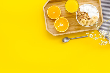 Bright breakfast with granola and orange juice on yellow background top view mockup