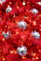 Background Silver mirror disco balls toys and lights on red indoor Christmas tree for New Year