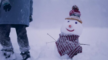 Two boys outdoors making a snowman in snowfall. Friendship and family weekends together concept.