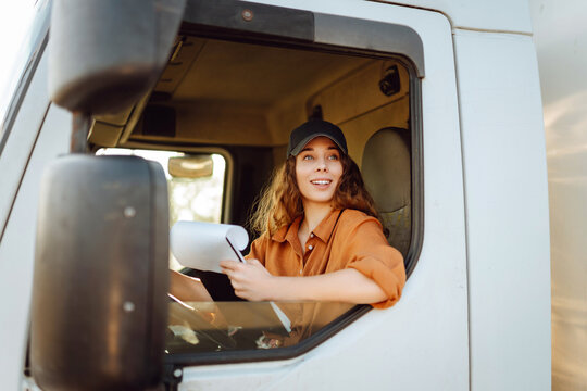 Young woman professional truck driver checking shipment list on a -parking lot. Transport industry theme.
