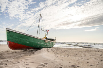Fototapeta premium Old green red abandoned wooden boat on a shores of Baltic sea