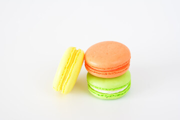 three different colored orange, yellow and green macaroons are stacked together