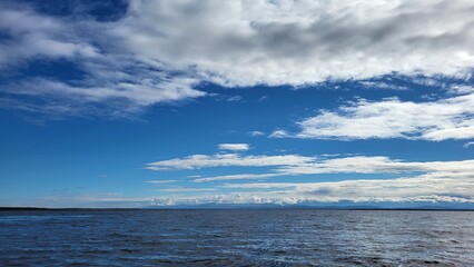 The blue lake merges on the horizon with the sky and white clouds
