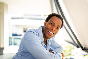 Obraz premium Man smiling while resting on balcony