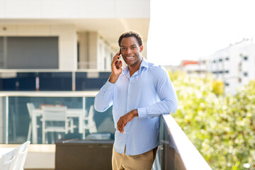 Smiling man on phone call while leaning on balcony railing