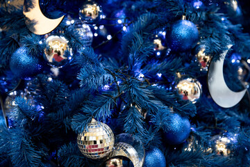 Background of silver, mirror, blue balls toys and lights on blue indoor Christmas tree for New Year
