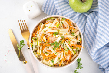 Homemade seasonal  Apple Slaw Salad with Apples, cabbage, carrot and spring onions. Healthy fall vegetable salad with yogurt dressing, in portioned bowls on kitchen table 